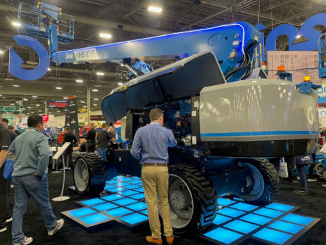 a group of people standing in a large room with a large blue machine